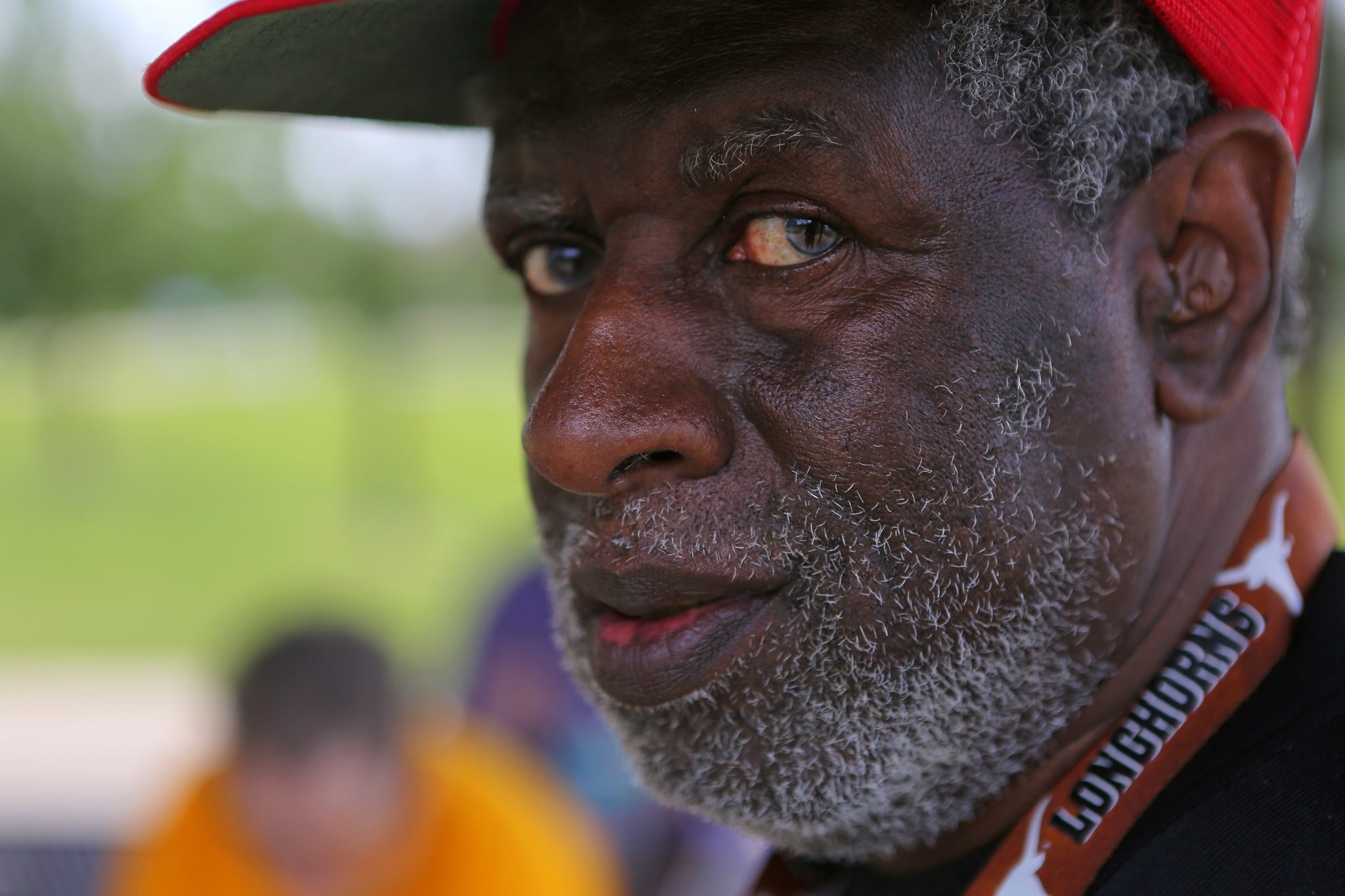 A man wearing a red baseball cap looks into the camera. 